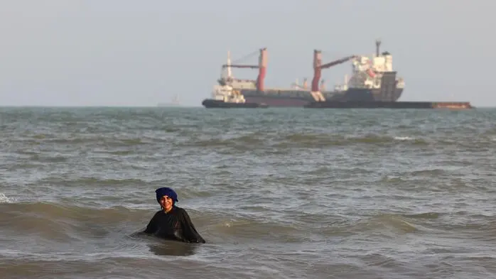 Iranische Frauen baden im Meer, während vor der Hafenstadt Bandar Abbas im Süden Irans Schiffe in der Straße von Hormuz zu sehen sind