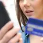 Worried woman pays online with credit card in the street