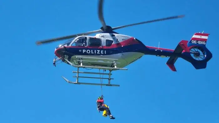 Das Bild zeigt eine Person, die an einem Tau am Polizeihubschrauber hängt