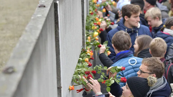 Gäste klemmen Blumen an das Mauer-Denkmal in Berlin.