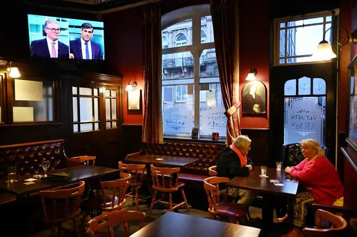 TOPSHOT - People have a drink in a pub, in Liverpool, north western England, on June 4, 2024 as a television broadcasts on the channel ITV, the first live TV debate between Britain's Prime Minister and Conservative Party leader Rishi Sunak and Britain's main opposition Labour Party leader Keir Starmer of the general election campaign. (Photo by Paul ELLIS / AFP)