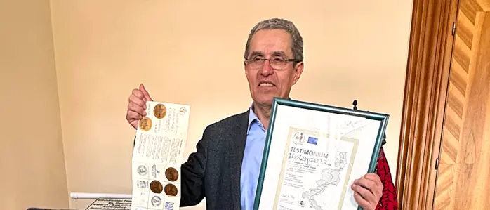 Ein Mann hält Urkunde in die Kamera