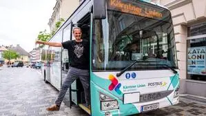 Ein Mann winkt aus der Türe eines Busses 