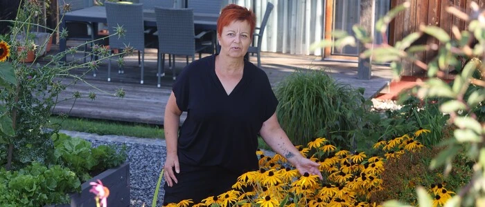 Zu sehen ist eine Frau mit kurzen roten Haaren inmitten ihrer Blumen