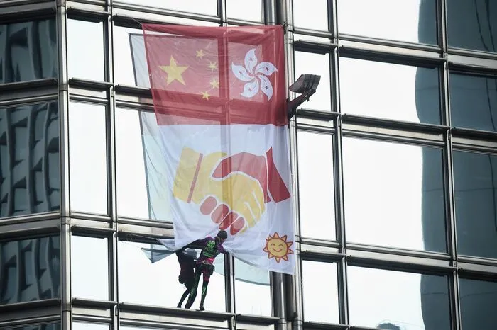 Dort entrollte er ein Banner, das die Flaggen Chinas und Hongkongs sowie zwei sich schüttelnde Hände zeigt. 