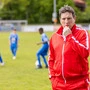 Fußballlegende Andi Herzog bläst in eine Trillerpfeife. Im Hintergrund trainieren drei Nachwuchsspieler