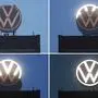 (FILES) In this combination of file photos taken on September 9, 2019 workers unveil an illuminated logo of German car maker Volkswagen (VW) at the company's headquarters in Wolfsburg, northern Germany. - German prosecutors charge the current and ex-VW CEOs with 'market manipulation' on September 24, 2019. (Photo by Julian Stratenschulte / dpa / AFP) / - Germany OUT