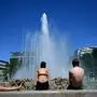 Menschen in Badekleidung an einem Brunnen in Wien
