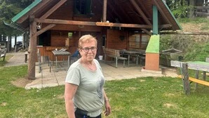 Eine ältere Dame steht vor einer Hütte 