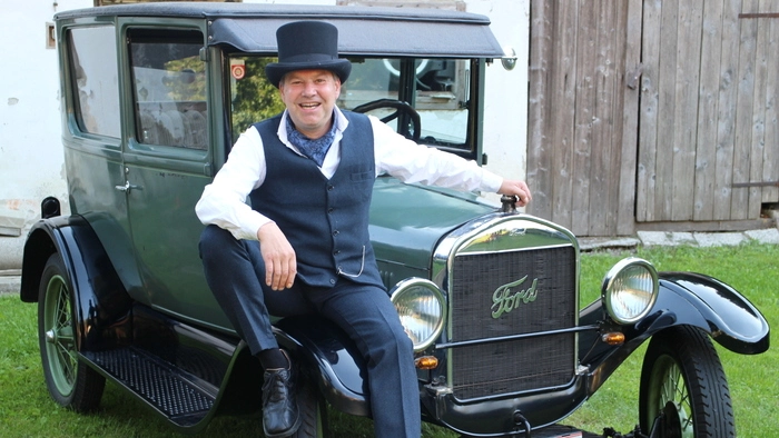 Mann mit Zylinder vor Oldtimer