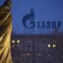 FILE - In this March 4, 2014 file photo, a monument to Ukrainian poet and writer Taras Shevchenko is silhouetted against an apartment building with a sign advertising Russia's natural gas giant Gazprom, in Moscow, Russia. Unsatisfied with a fragile cease-fire in Ukraine, the United States and the European Union levied new sanctions Friday against major Russian banks and defense companies, as well as penalties aimed at curtailing Russia's ability to develop oil and gas projects. But the restrictions on Russia's energy sector were carefully crafted to avoid impacting the country's current production of oil and gas, a move that would raise global energy prices at time of weak economic growth. Russia is the largest oil exporter outside of OPEC and the most important supplier of natural gas to Europe. (AP Photo/Alexander Zemlianichenko, file)