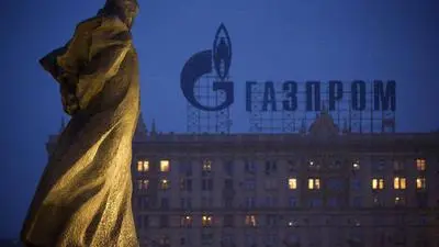 FILE - In this March 4, 2014 file photo, a monument to Ukrainian poet and writer Taras Shevchenko is silhouetted against an apartment building with a sign advertising Russia's natural gas giant Gazprom, in Moscow, Russia. Unsatisfied with a fragile cease-fire in Ukraine, the United States and the European Union levied new sanctions Friday against major Russian banks and defense companies, as well as penalties aimed at curtailing Russia's ability to develop oil and gas projects. But the restrictions on Russia's energy sector were carefully crafted to avoid impacting the country's current production of oil and gas, a move that would raise global energy prices at time of weak economic growth. Russia is the largest oil exporter outside of OPEC and the most important supplier of natural gas to Europe. (AP Photo/Alexander Zemlianichenko, file)