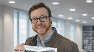 Mann mit Brille hält einen Kalender in die Kamera