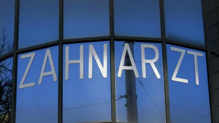 Eine Glasfassade mit einer Schrift - "Zahnarzt", Ordination, Wien. Österreich.
