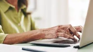 Blick auf einen Laptop, wo eine Frau gerade darauf tippt