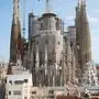 Das Bild zeigt die berühmte Basilika <strong>Sagrada Família</strong> in Barcelona, Spanien. Das monumentale Bauwerk befindet sich weiterhin im Bau, was durch die zahlreichen Baugerüste und Kräne deutlich wird. Im Vordergrund sieht man Wohngebäude, während sich dahinter die eindrucksvollen, reich verzierten Türme der Basilika in den Himmel erheben. Die markante Mischung aus gotischen und modernistischen Elementen sowie die aufwendige Fassadengestaltung sind typisch für den Architekten Antoni Gaudí. | Seit 1882 wird an Gaudís Meisterwerk gearbeitet. Nun ist ein Ende in Sicht