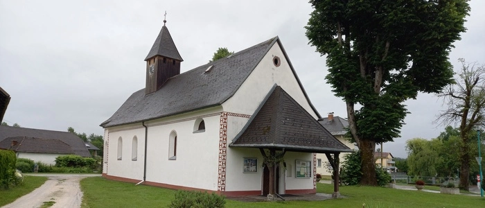 Zu sehen ist eine  Pfarrkirche mit einem Holz-Glockenturm