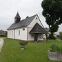 Zu sehen ist eine  Pfarrkirche mit einem Holz-Glockenturm 