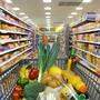 Ein Einkaufswagerl fährt zwischen vollen Supermarktregalen durch | Der Einkauf im Supermarkt ist nicht günstig