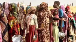 People who fled the Zamzam camp for the internally displaced after it fell under RSF control, queue for food rations in a makeshift encampment in an open field near the town of Tawila in war-torn Sudan's western Darfur region on April 13, 2025. The United Nations says more than 400 people have been killed and around 400,000 people displaced since the RSF on Friday began attacking Zamzam, where aid sources estimate up to a million people were sheltering. (Photo by AFP)