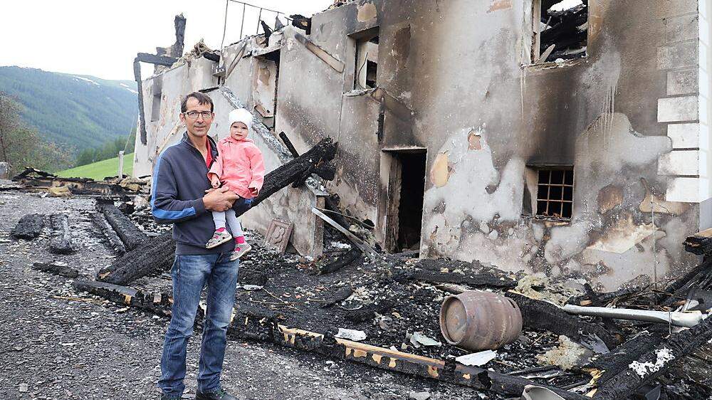 Bernhard Miedl mit Enkelin Marie vor seinem Haus in Oberwölz, das bei einem Brand zerstört wurde