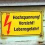 Foto einer gelben Hinweistafel, die auf Hochspannung und Lebensgefahr hinweist