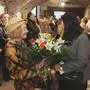 Zwei Damen begrüßen sich mit einem Blumenstrauß