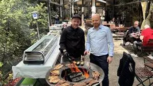 Die beiden Herren stehen am Grill im Gastgarten