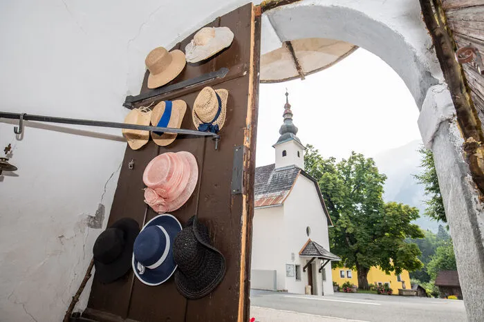 Die Hüte an der Eingangstüre erinnern an die Hochzeiten, die Elke Piskernik besucht hat. Im Hintergrund ist die Kirche zu sehen, die auf der anderen Straßenseite ist.
