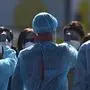 Workers in protective clothes measures the body temperature of a passenger disembarking from the Diamond Princess cruise ship, in quarantine due to fears of new COVID-19 coronavirus, at Daikoku pier cruise terminal in Yokohama on February 21, 2020. - Hundreds of people have been allowed to leave the ship after testing negative for the disease and many have returned to their home countries to face further quarantine. (Photo by Philip FONG / AFP)
