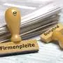 Firmenpleite An einem Papierstapel lehnt ein Holzstempel mit dem Aufdruck: Firmenpleite und Prüfung *** Company bankruptcy A wooden stamp with the words company bankruptcy and audit leans against a pile of paper