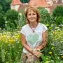 Die Obfrau des Vereins „Blühen&summen“ kniet inmitten einer bunt blühenden Wildblumenwiese  | Christine Podlipnig setzt sich seit Jahren für die Wiederherstellung naturbelassener Wiesen ein 