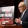 Chuck Schumer, Fraktionsführer der Demokraten im US-Senat, steht vor einem Rednerpult, neben ihm steht ein Schild mit der Aufschrift „Rein in ICE + Stop violence“