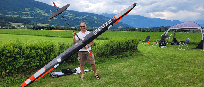 Ein Mann hält ein großes Modellflugzeug in den Händen.