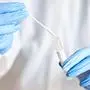 Doctor holding swab test tube for 2019-nCoV analyzing. Coronavirus test. Blue medical gloves and protective face mask for protection against covid-19 virus. Coronavirus and pandemic