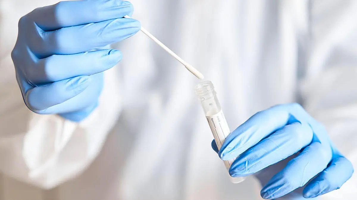 Doctor holding swab test tube for 2019-nCoV analyzing. Coronavirus test. Blue medical gloves and protective face mask for protection against covid-19 virus. Coronavirus and pandemic