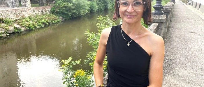 Zu sehen ist eine Frau mit kinnlagen braunen Haaren. Im Hintergrund ist ein Fluss zu sehen 