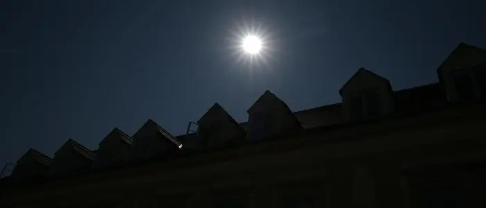 Man sieht die Sonne über Hausdächern