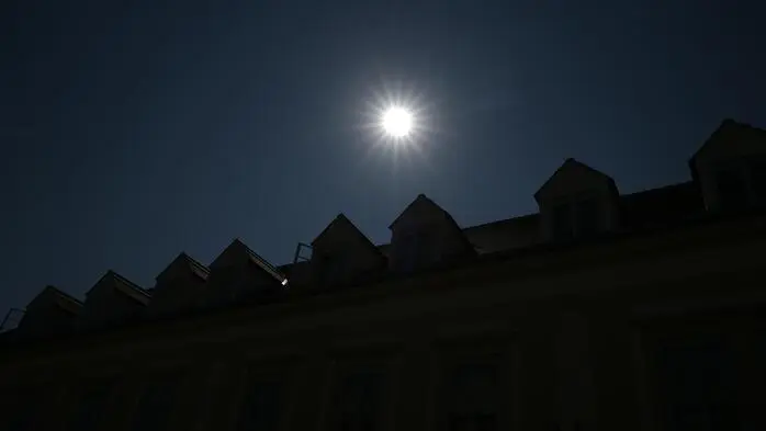 Man sieht die Sonne über Häuserspitzen
