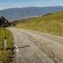 Straße mit Fahrbahnschäden vor Bergpanorama