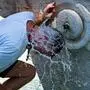 Ein Mann kühlt seinen Kopf unter dem Wasserstrahl eines öffentlichen Brunnens