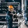 Portrait of young Caucasian man dressed in work wear using tablet while standing in heating plant.