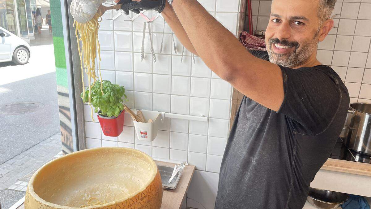 Ehab Omar schwenkt Nudeln in Parmesan