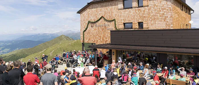 Vor der Sillianer Hütte feiern viele Menschen die Neueröffnung im Jahr 2023