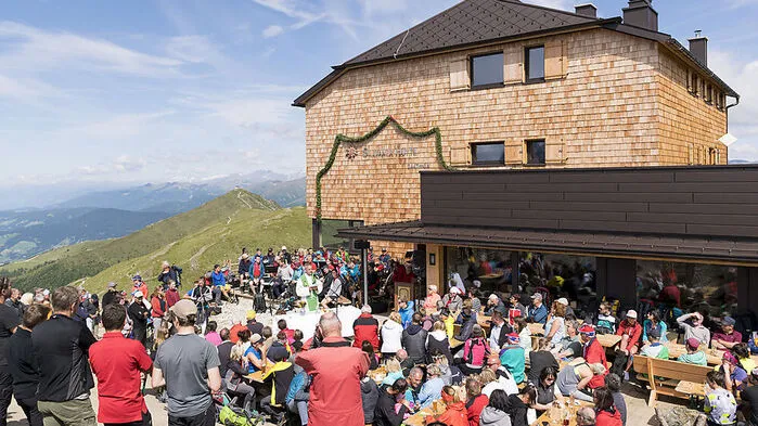 Vor der Sillianer Hütte feiern viele Menschen die Neueröffnung im Jahr 2023