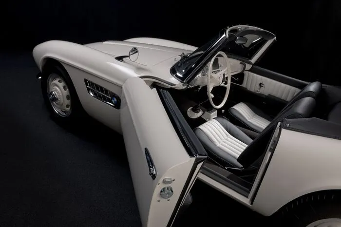 Mit einer Lackierung in Federweiß, dem 150 PS starken V8-Aluminium-Triebwerk unter der Motorhaube, Zentralverschluss-Felgen, schwarz-weißem Interieur und einem Radio vom Typ Becker Mexico.