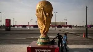 Men walk past a FIFA World Cup trophy replica outside the Ahmed bin Ali Stadium in Al-Rayyan on November 12, 2022, ahead of the Qatar 2022 FIFA World Cup football tournament. (Photo by Kirill KUDRYAVTSEV / AFP)