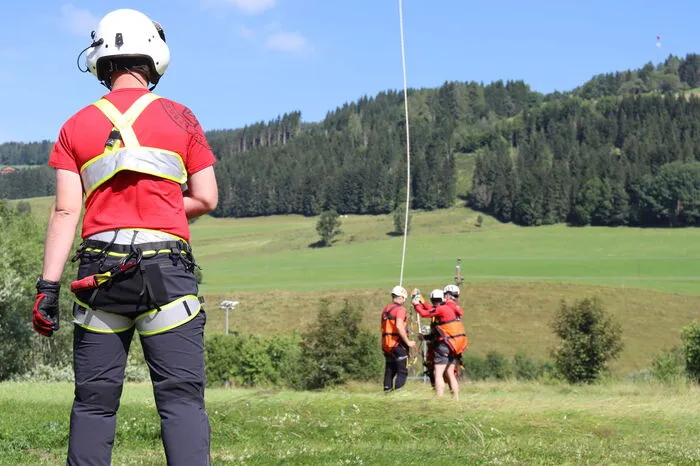 Flug- und Bergretter hängen an sich an ein gemeinsames Tau …