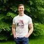 MFG-Spitzenkandidat Andreas Winkler posiert mit T-Shirt, Hände locker in die Hosentasche gesteckt; im Hintergrund Bäume