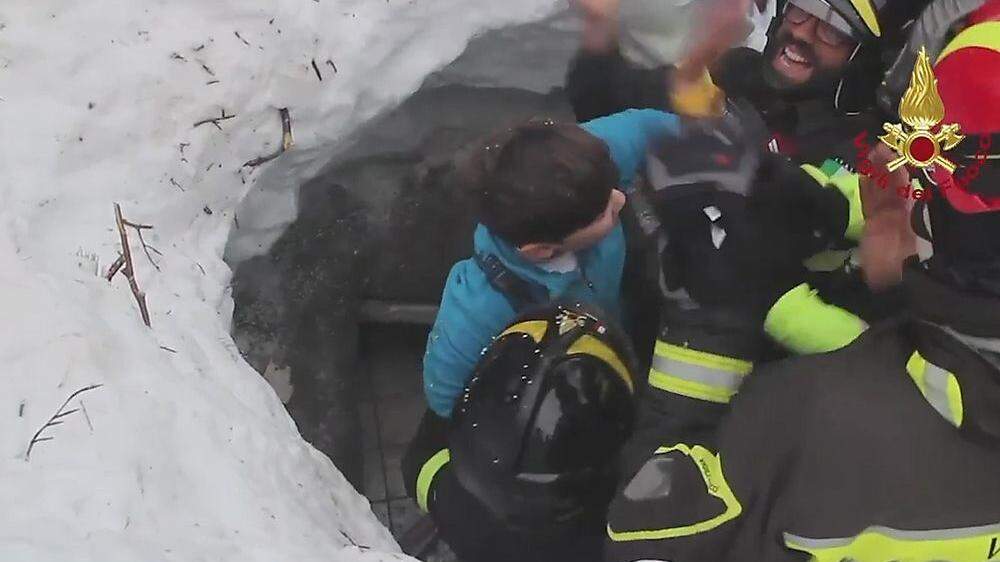 Einsatzkräfte bergen ein Kind aus dem verschütteten Hotel.